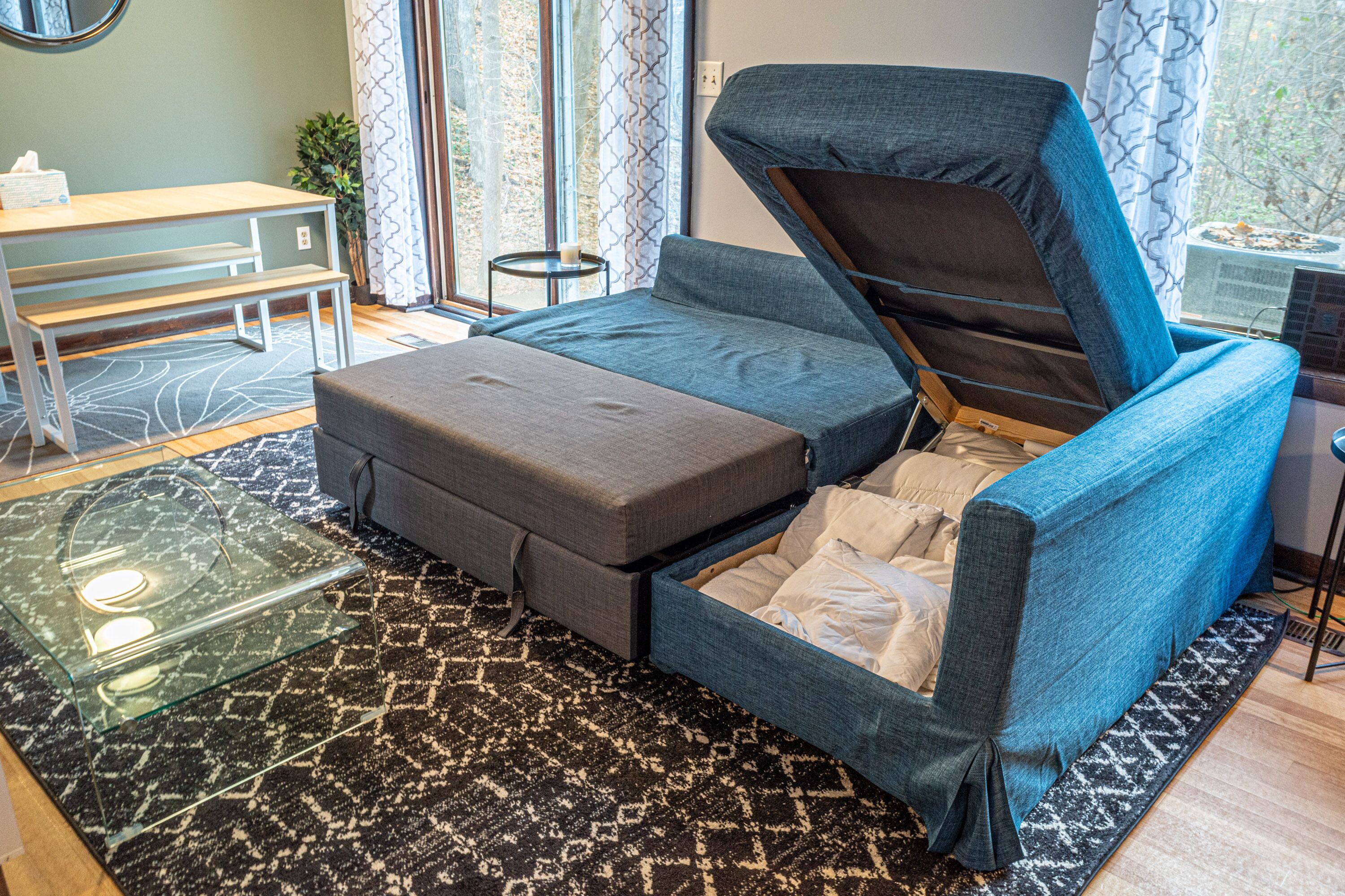 A modern room with a sofa bed, a small table, and a glass coffee table.