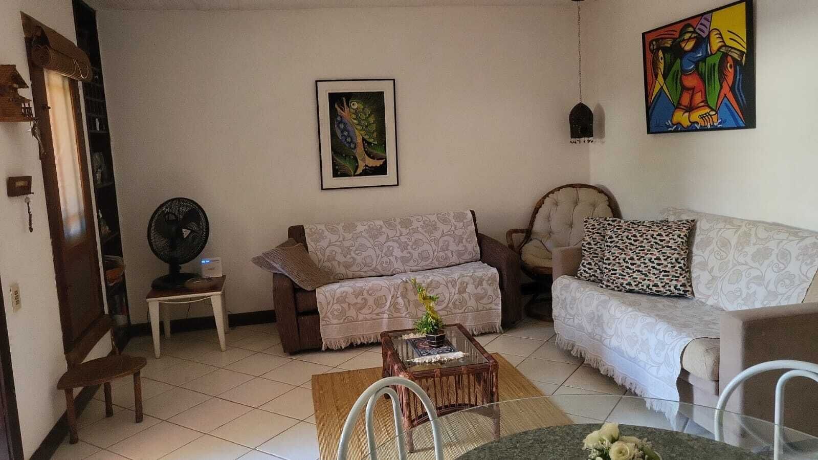 A living room with two sofas, a coffee table, a fan, and a painting on the wall.
