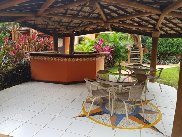 Une terrasse extérieure avec une table ronde et des chaises, entourée d’un sol carrelé orné d’un motif en étoile.