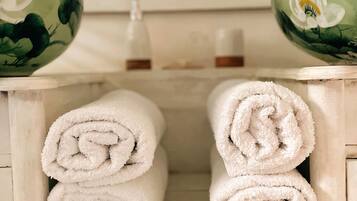 Un baño con toallas blancas, una botella de loción y cuencos decorativos.
