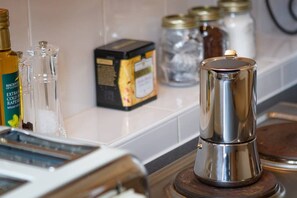 Un comptoir de cuisine avec une machine à café, une boîte de capsules de café et divers pots.