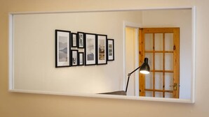 A hallway with framed pictures on the wall, a lamp, and a wooden door. - Cozy Apartment near The Meadows (Edinburgh)
