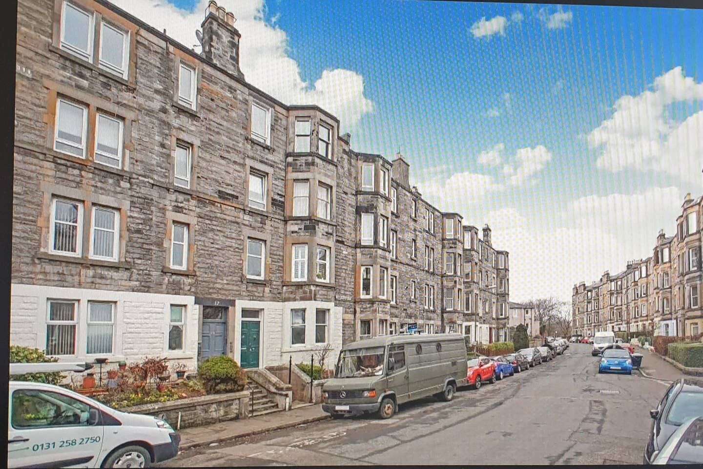 A row of terraced houses with a parked camper van and cars on the street.