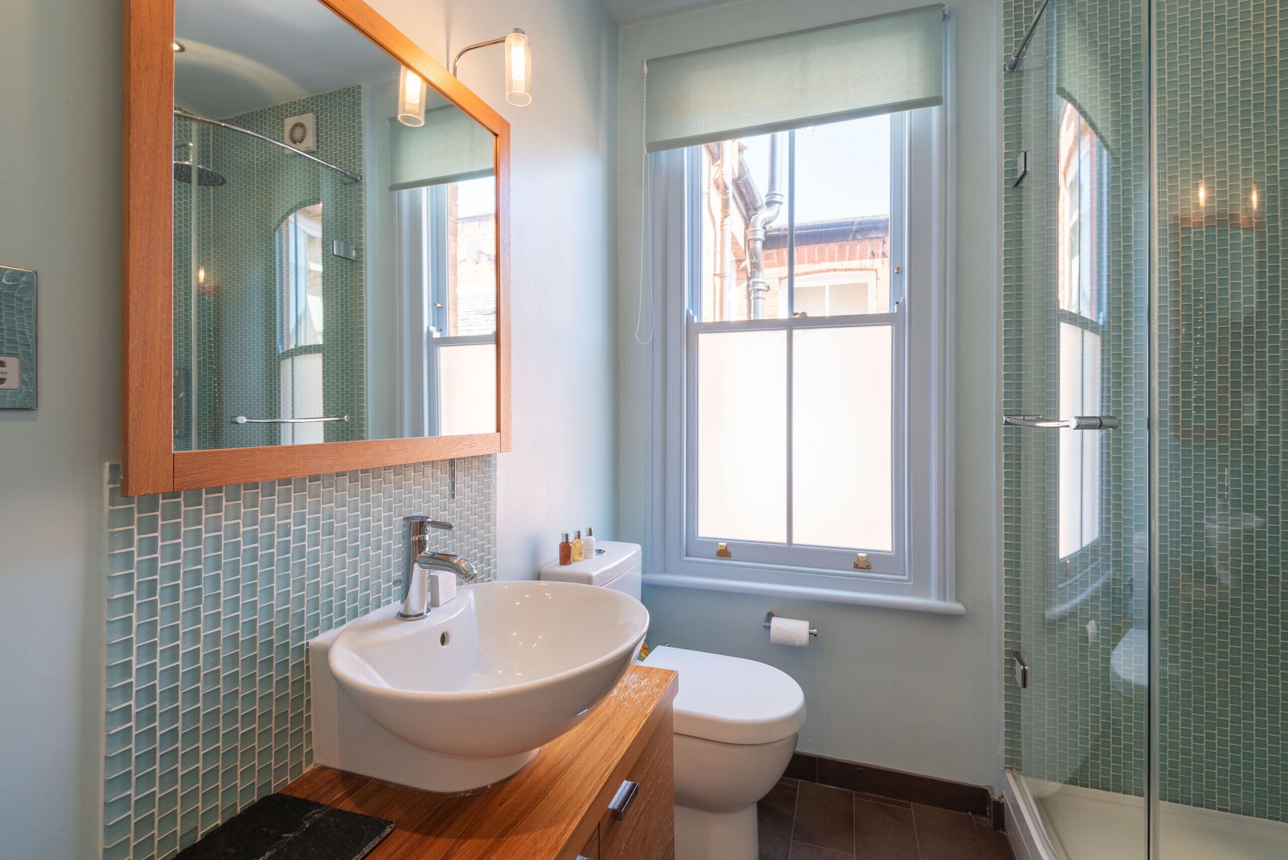 A bathroom with a large mirror, a sink, a toilet, and a shower.
