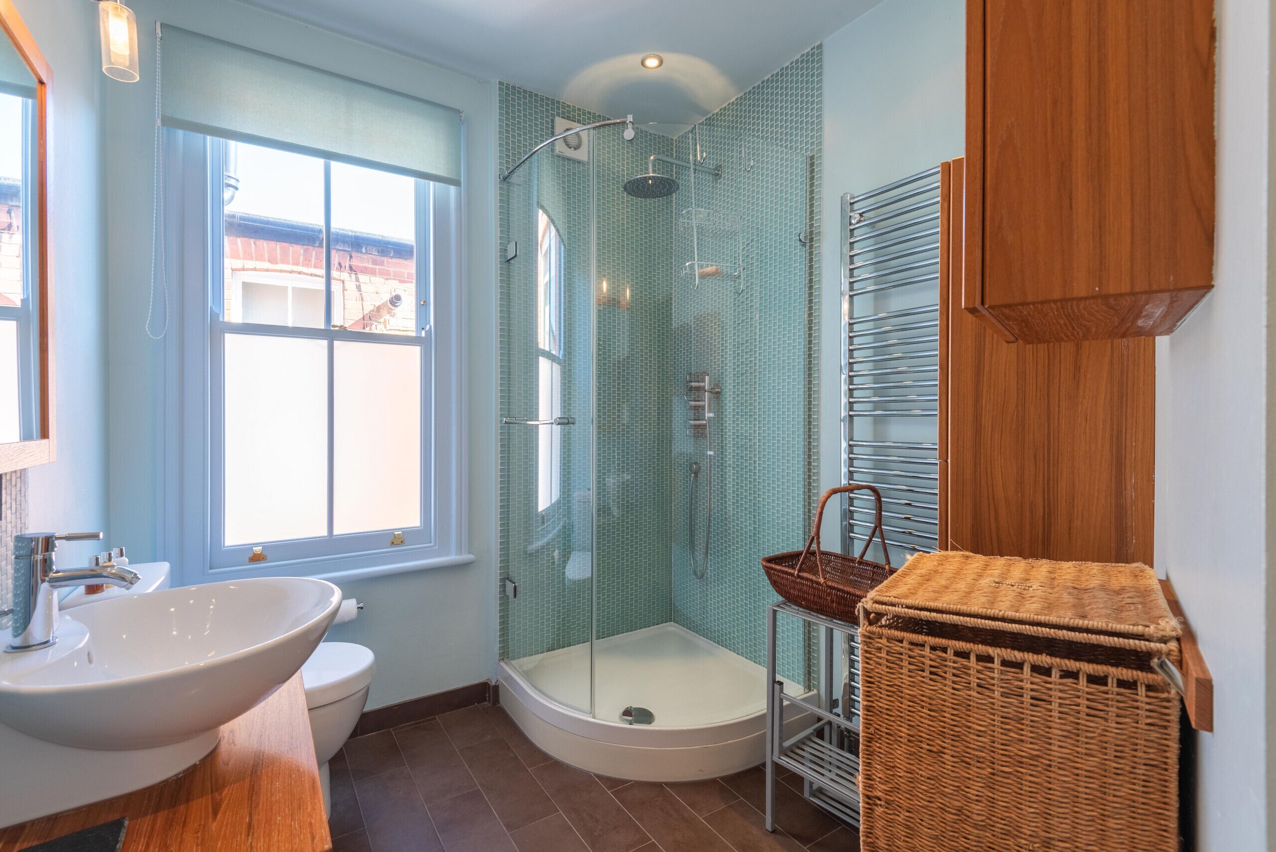 Une salle de bain avec un grand lavabo, des toilettes et une douche fermée par des parois en verre.