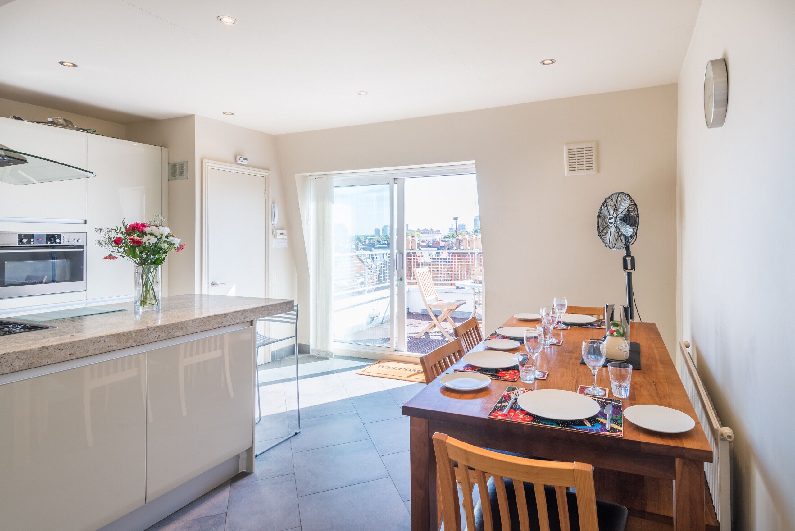 A modern kitchen with a built-in oven and a dining area with a wooden table set for four.
