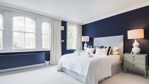 A bedroom with a large bed, two bedside tables, a radiator, and a window with curtains. - A Home on Northcote (London)