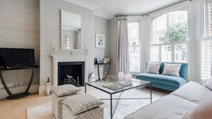 A modern living room with a fireplace, a sofa, a coffee table, and a television. - A Home on Northcote (London)