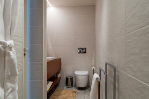A modern bathroom with a wooden vanity, a toilet, a trash can, and a towel rack. - Portugal Boutique Winery Apartments (Vila Nova de Gaia)