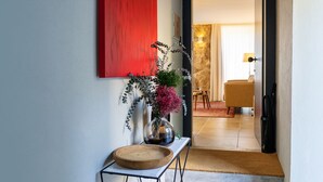 A hallway with a red accent wall, a vase with flowers, and a wooden tray on a table. - Portugal Boutique Winery Apartments (Vila Nova de Gaia)