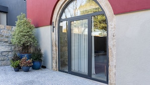 A modern building with a red facade, a stone wall, and a large glass door with a curtain. There are potted plants in front. - Portugal Boutique Winery Apartments (Vila Nova de Gaia)