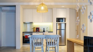 A modern kitchen with white cabinetry, a stainless steel refrigerator, and a dining area with two white chairs. - Portugal Boutique Winery Apartments (Vila Nova de Gaia)