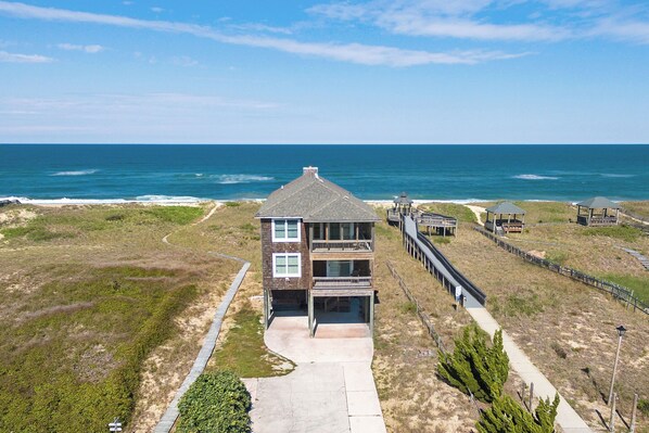 Une maison de deux étages située en bord de mer, dotée d’un balcon, d’une véranda et offrant une vue sur l’océan.