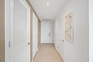 A hallway with white doors, a wooden floor, and a ceiling light.