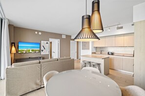 A modern living room with a sofa set, a dining table, and a kitchen area with a central island.