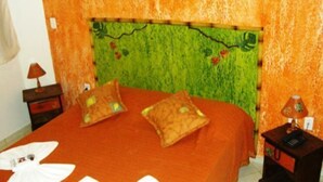 A room with a bed, two nightstands, and a wall with a green and orange pattern. - Peruibe Suites Flat (Peruíbe)