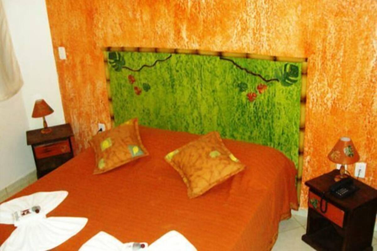 A room with a bed, two nightstands, and a wall with a green and orange pattern.