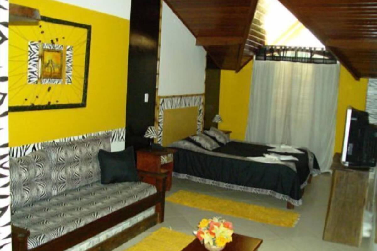 A room with a bed, a sofa, a television, and a decorative wall piece.