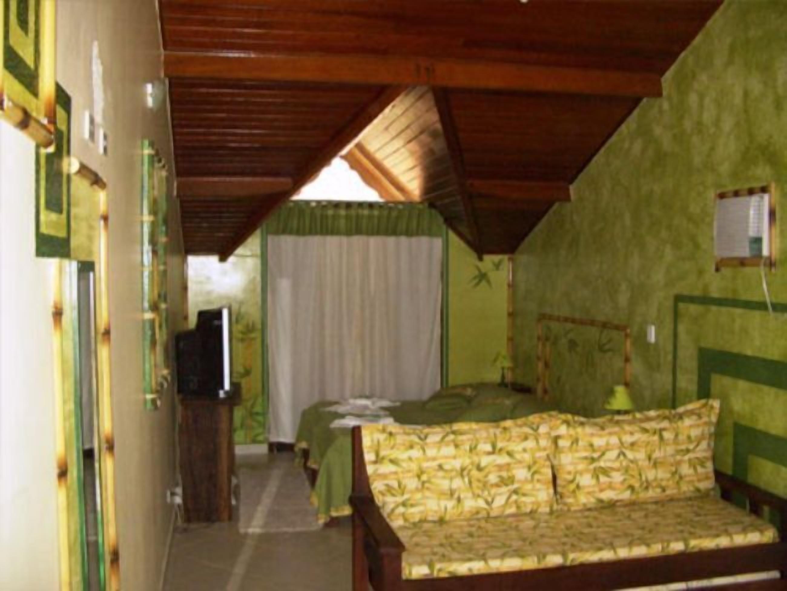 Una habitación con una cama, televisión y pared verde.