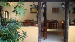Un espace patio intérieur aménagé avec des meubles en bois, des plantes en pot et des luminaires fixés au mur.