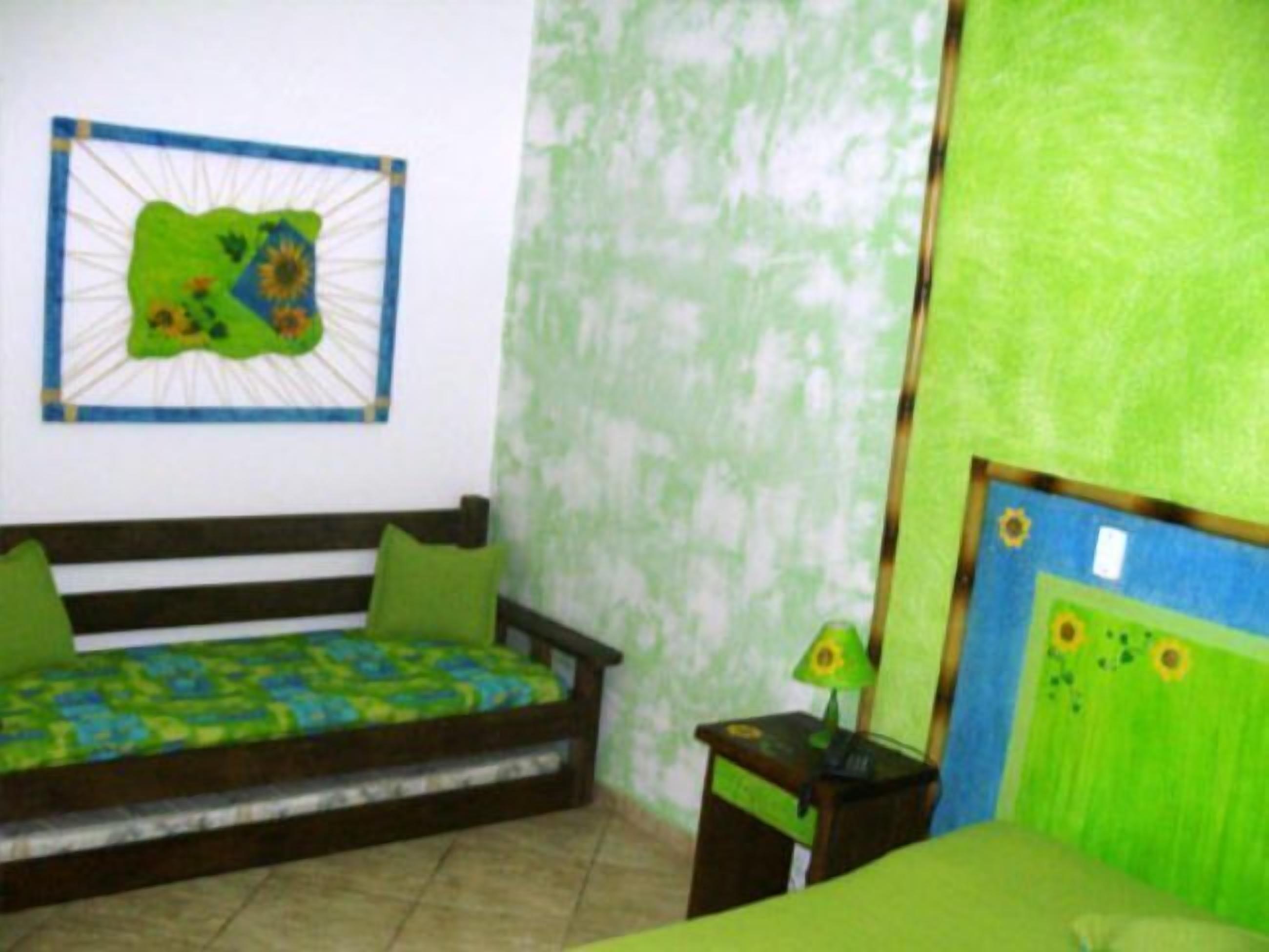 Una habitación con una cama, una mesita de noche con una lámpara y una pared con un mural verde.