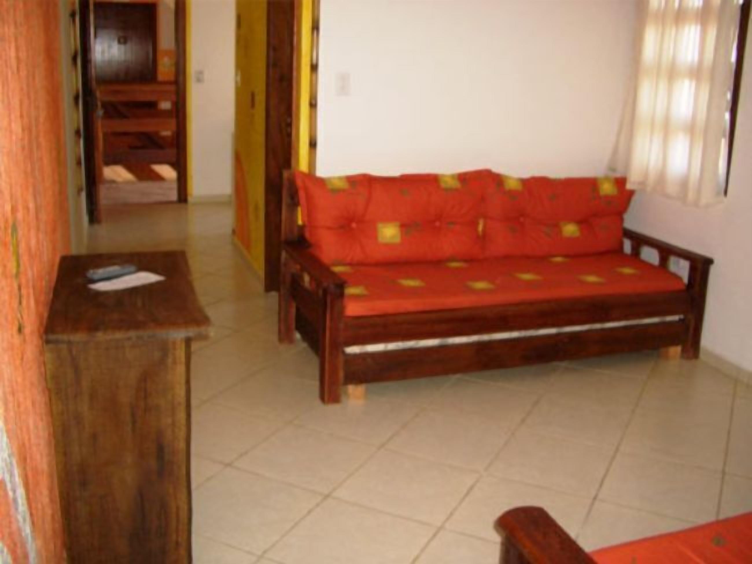 Ein Zimmer mit einer Holzsofa, einem kleinen Tisch und einer Tür zu einem weiteren Raum.