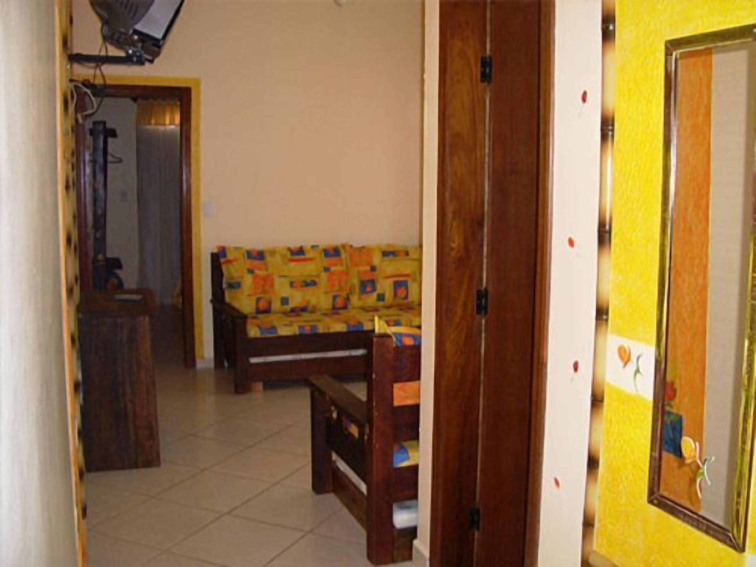 Una habitación con un sofá, un banco de madera, una mesita y una puerta con un espejo.