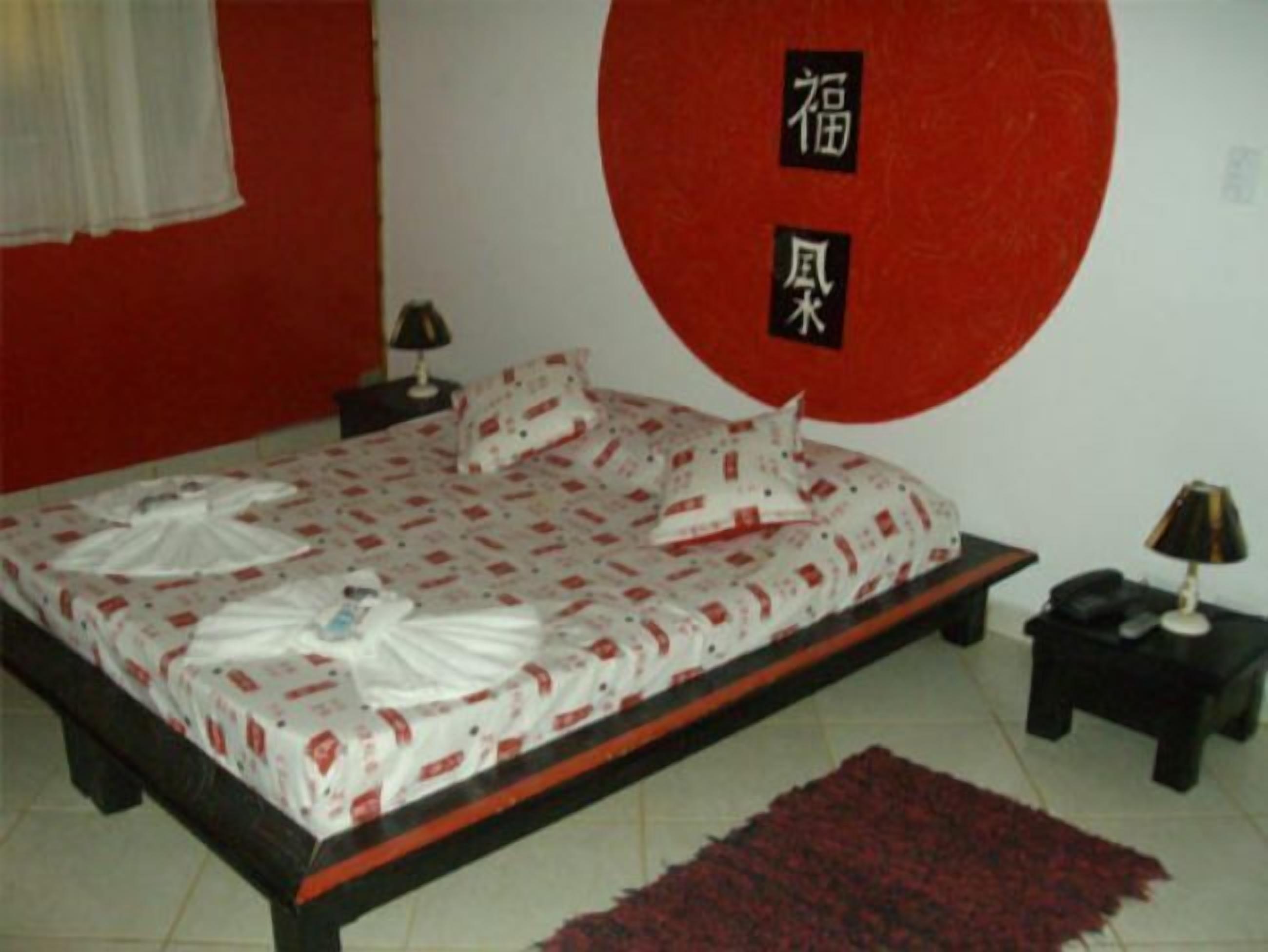 Una camera da letto con un letto, un comodino, una lampada e un tappeto rosso.