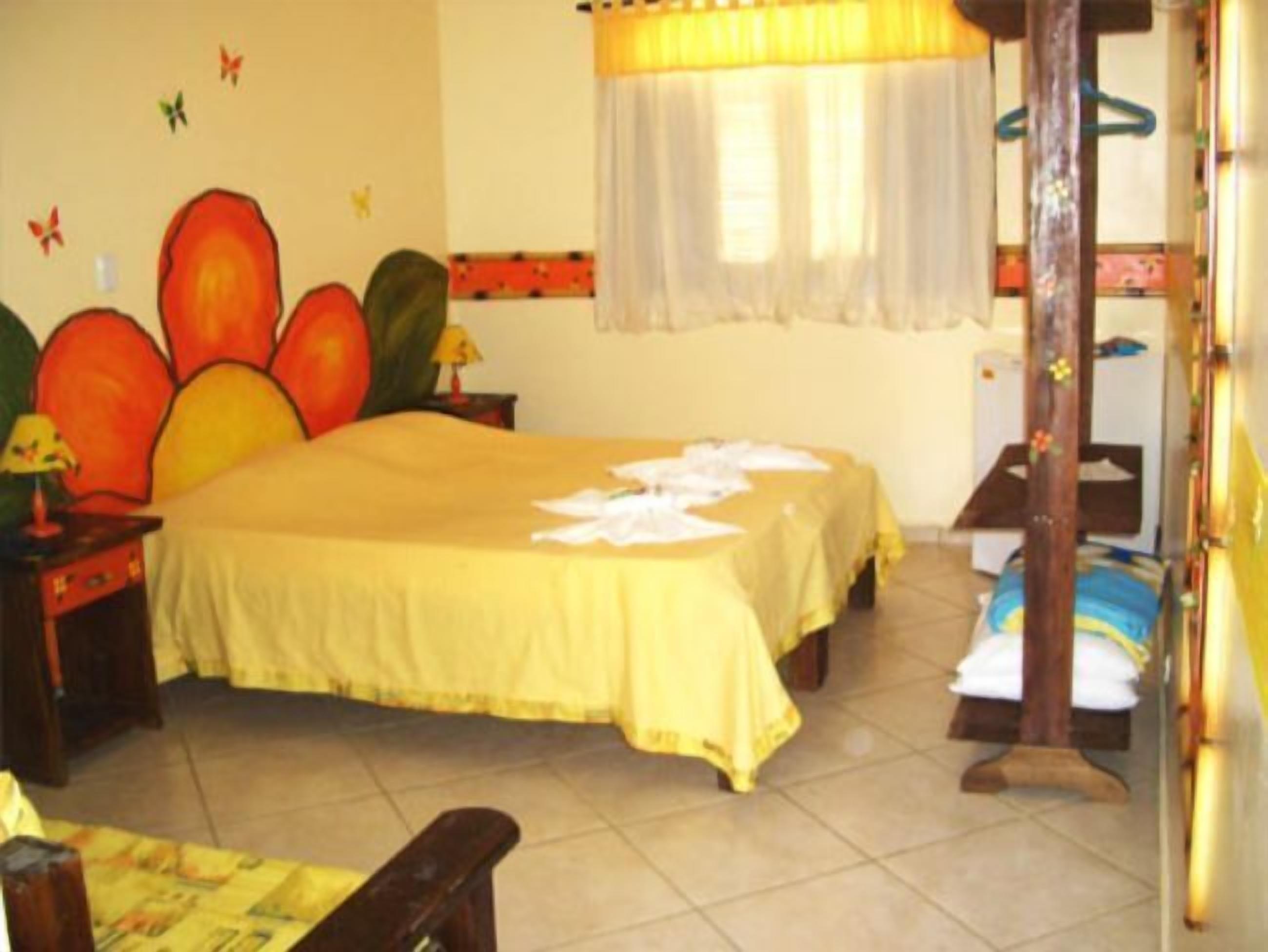 A hotel room with a bed, a nightstand, a chair, and a wooden bed frame.