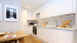 A modern kitchen with white cabinets, a wooden dining table, and a microwave.