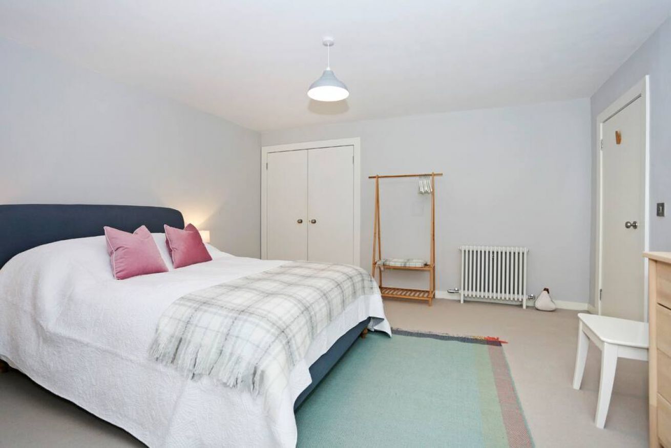 A bedroom with a bed, a bedside table, a radiator, and a wardrobe.