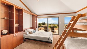 Un dormitorio con cama, armario de madera, balcón con vistas y escalera de madera.
