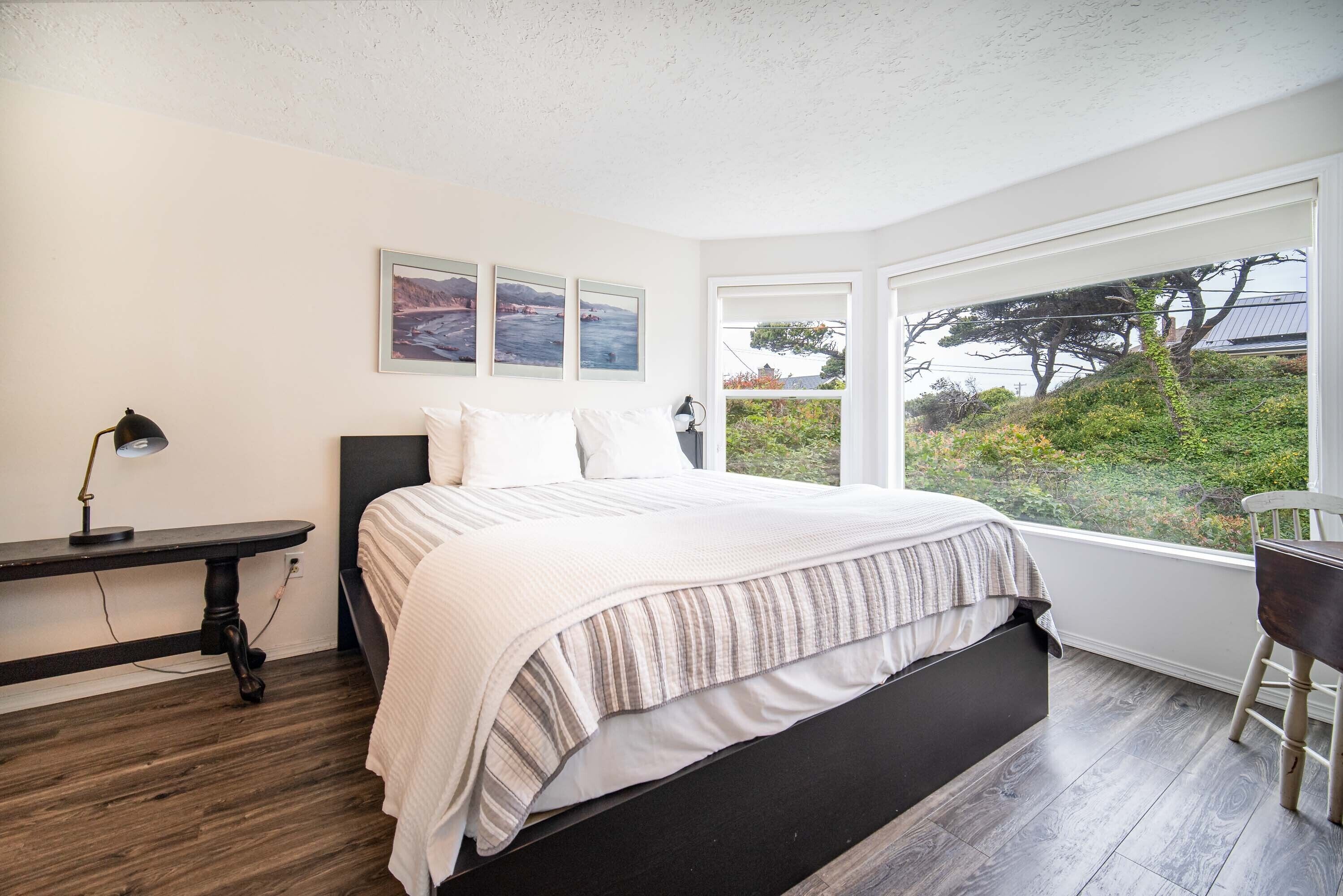 A bedroom with a bed, a desk, and a chair. There are three framed pictures on the wall.
