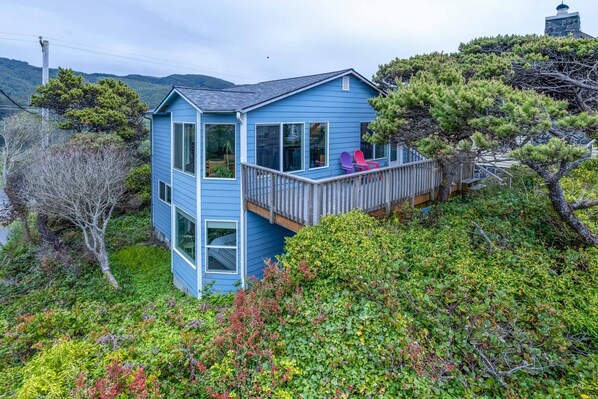 A two-story blue house with a balcony, surrounded by dense greenery and trees. - Beach Home with Ocean and Lake Views and Easy Beach Access (Rockaway Beach)