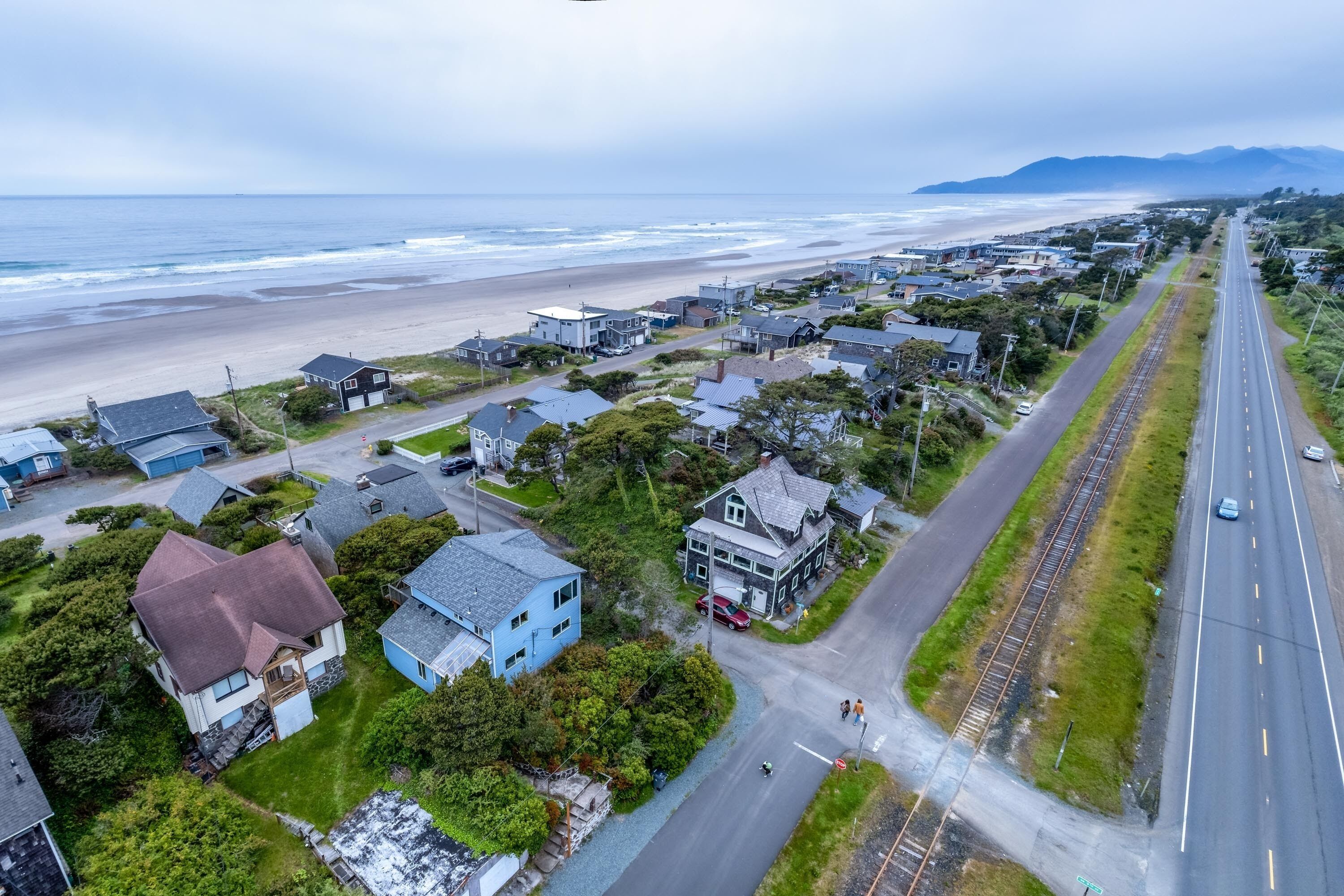 Vista aérea de una zona residencial costera con casas, una playa y una carretera.