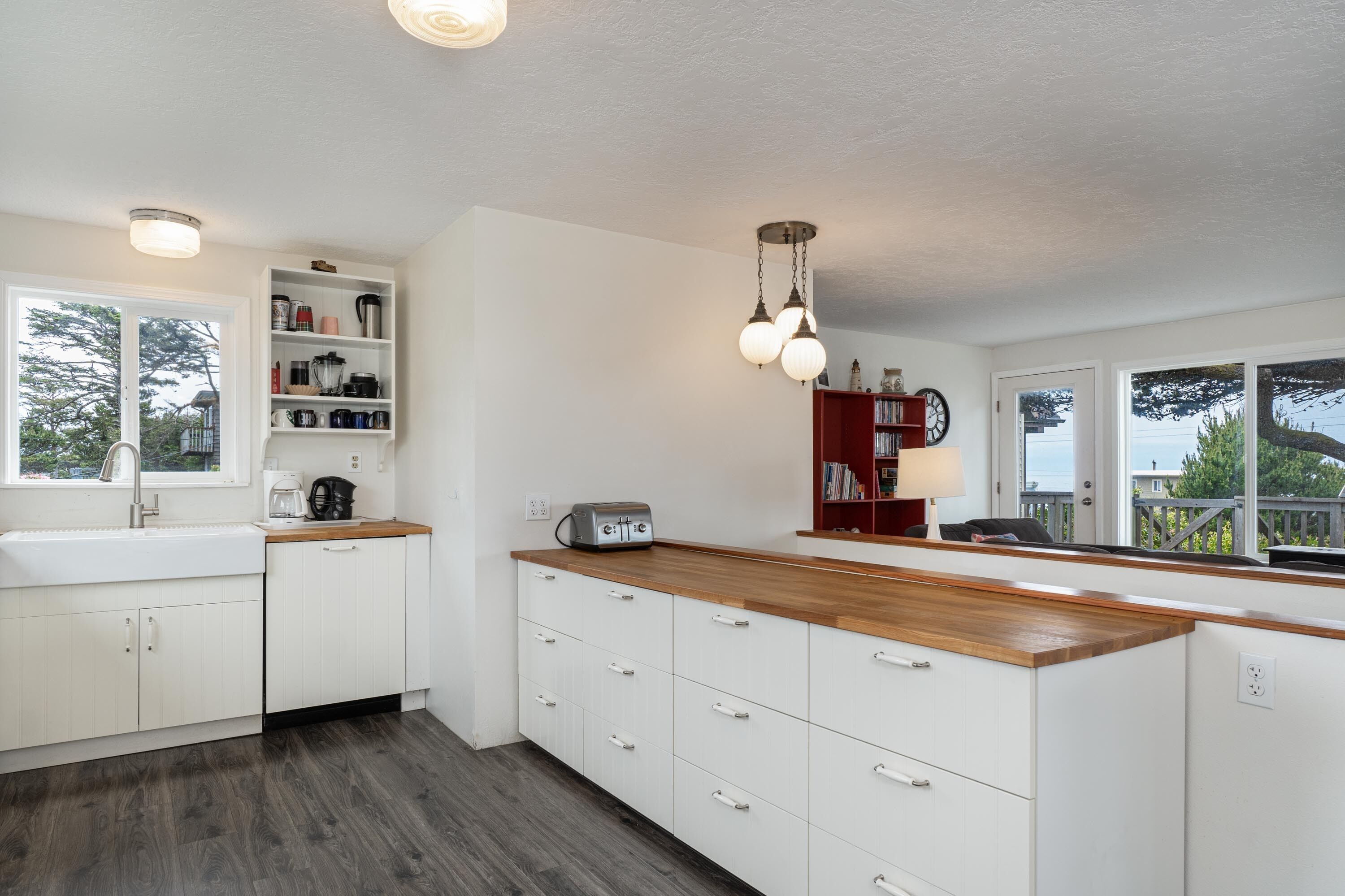 Une cuisine moderne avec des meubles blancs, un plan de travail en bois et une bibliothèque intégrée.
