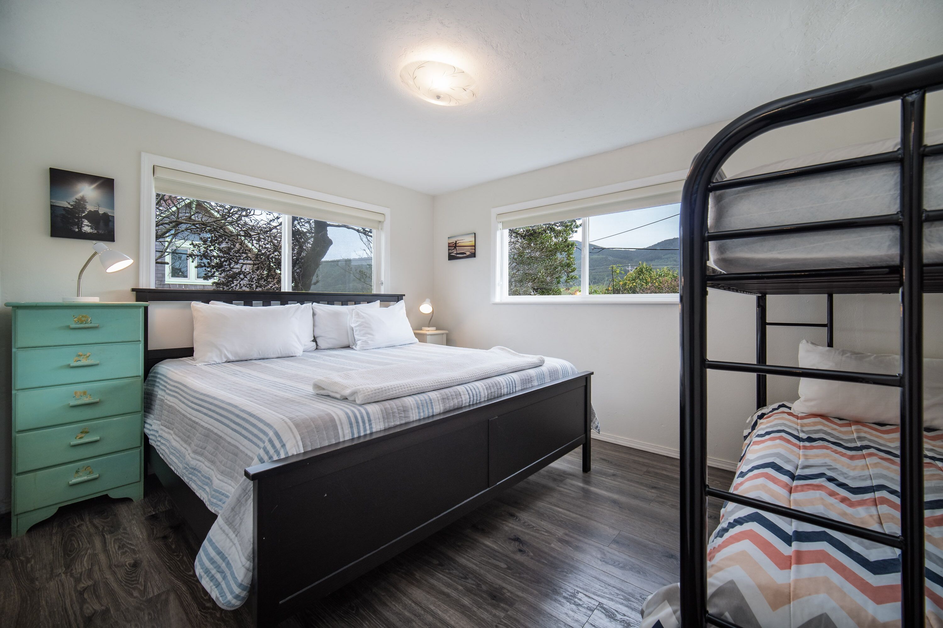Un dormitorio con cama, cómoda y literas.