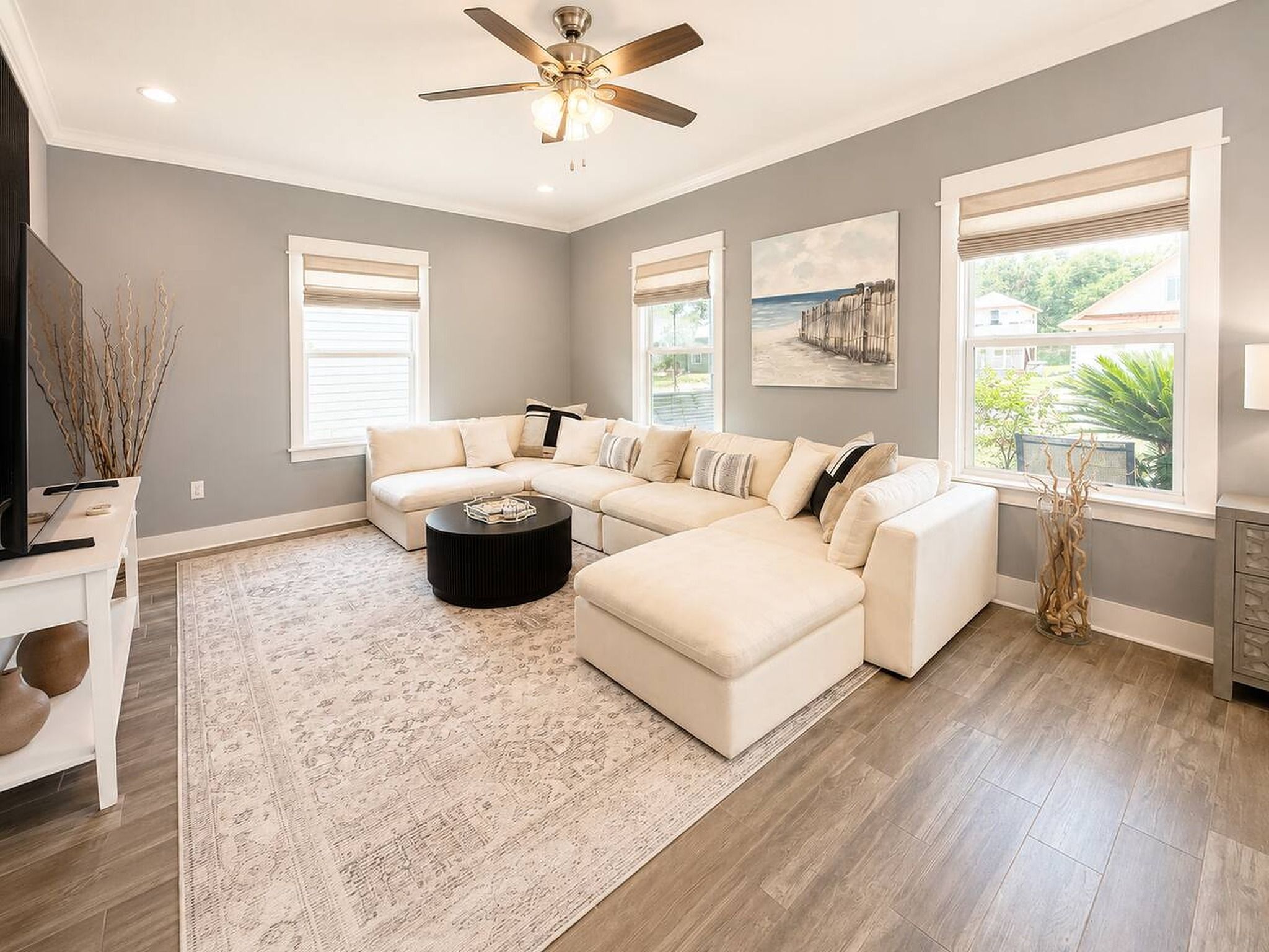 A modern living room with a sectional sofa, a coffee table, and a ceiling fan.