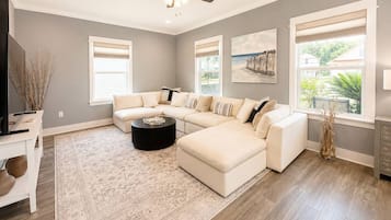 A modern living room with a sectional sofa, a coffee table, and a ceiling fan.