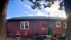 A red house with a porch, two red Adirondack chairs, a small table, and a white picket fence. - ⭐️Tranquil Hidden Gem in the ❤️ of Woodstock⭐️ (Portland)