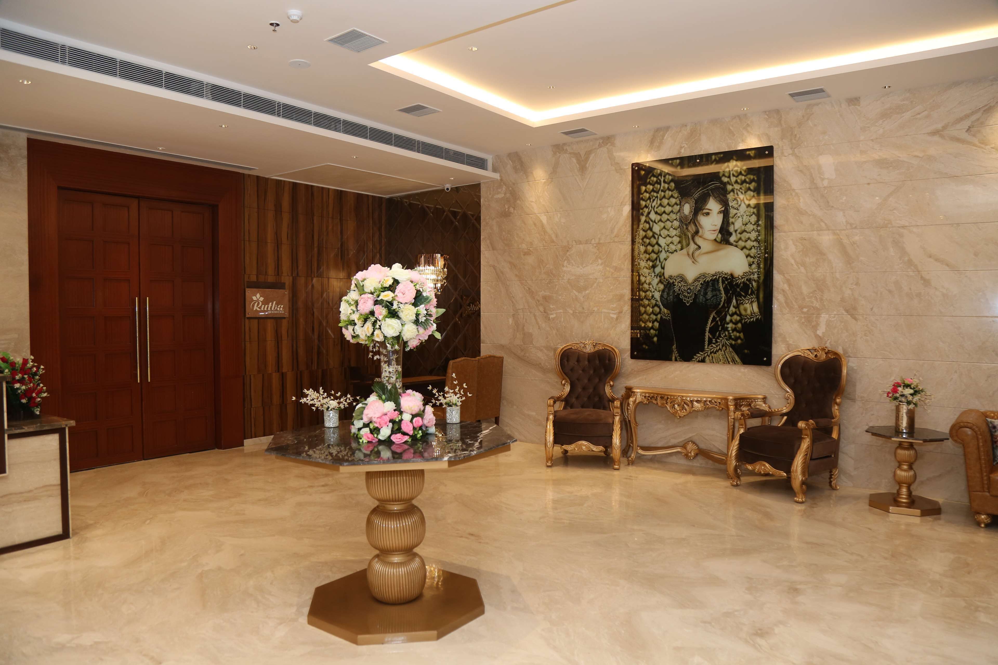 A lobby with a marble floor, a large floral centerpiece, a grand chandelier, and elegant furniture.