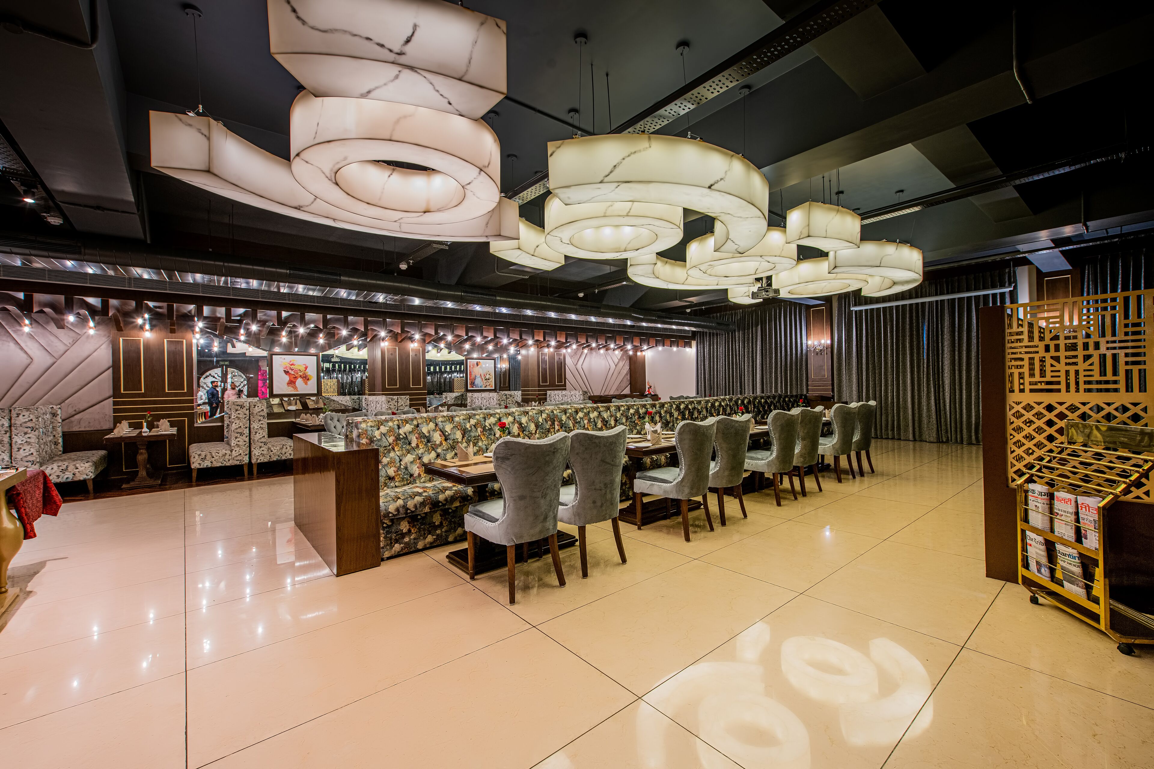 Un restaurante moderno con una zona de estar central, varias mesas de comedor y una lámpara decorativa en el techo.