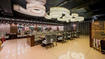 Un restaurante moderno con una zona de estar central, varias mesas de comedor y una lámpara decorativa en el techo.