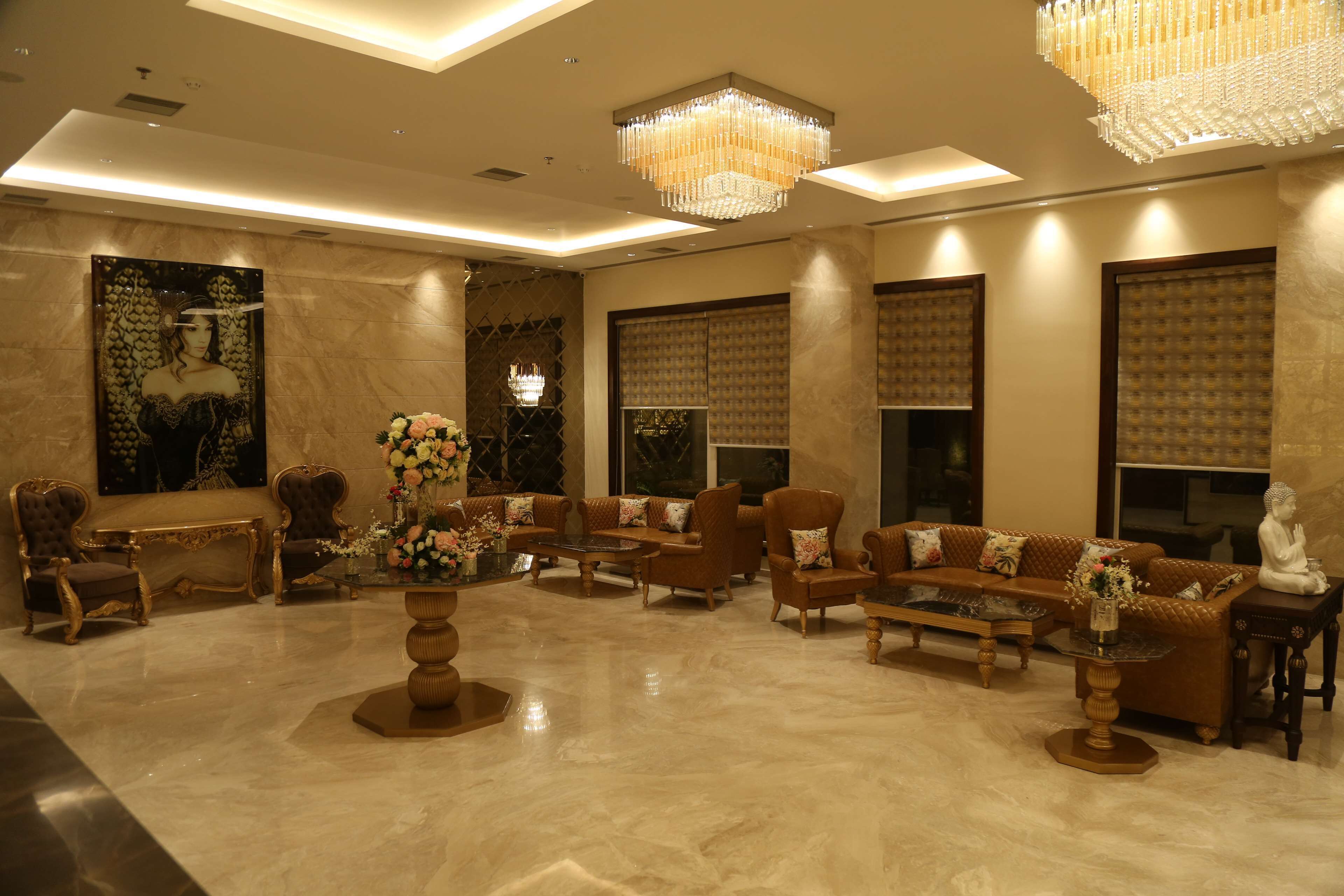 A spacious lobby with a high ceiling, chandeliers, and a large painting on the wall.