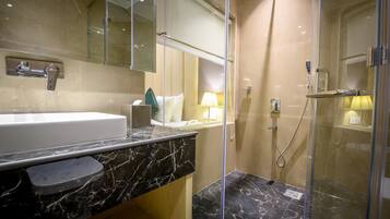A modern bathroom with a marble sink, a glass-enclosed shower, and a large mirror.