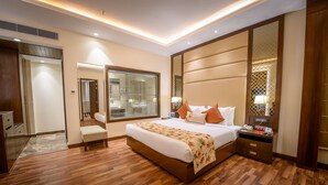 A modern hotel room with a large bed, wooden flooring, a walk-in closet, and a bathroom with a glass shower. - Best Western Kapurthala (Kapurthala)