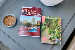 Two books titled '60 Hikes Within 60 Miles' and 'Richmond, VA' with a coin and a white object on a table. - Sunny Cottage At Byrd Pard In Richmond (Richmond)