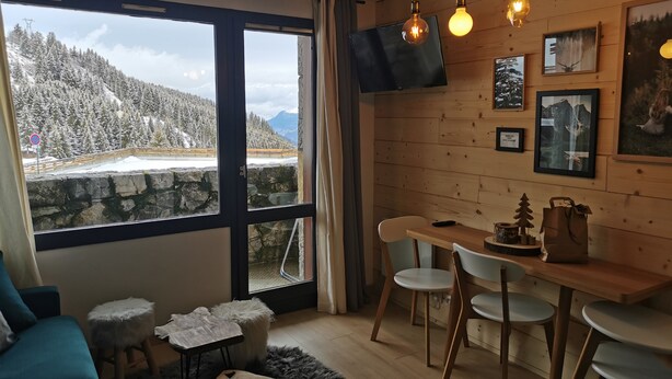 A cozy room with a large window overlooking a snowy mountain landscape. - APARTMENT 4/6 people AT THE FOOT OF THE SLOPES (Méribel-Mottaret)
