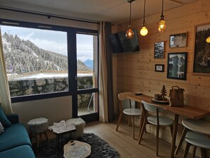 A cozy room with a large window overlooking a snowy mountain landscape.