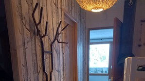 A hallway with a wooden door, a wall-mounted decor resembling tree branches, and a white bench. - APARTMENT 4/6 people AT THE FOOT OF THE SLOPES (Méribel-Mottaret)